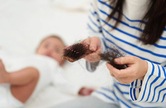 Woman with hair in brush and baby in background