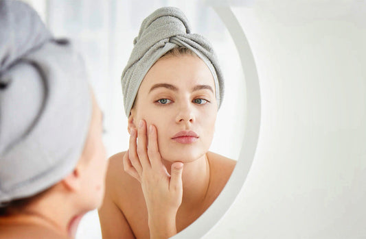 Woman with towel on head looking in mirror