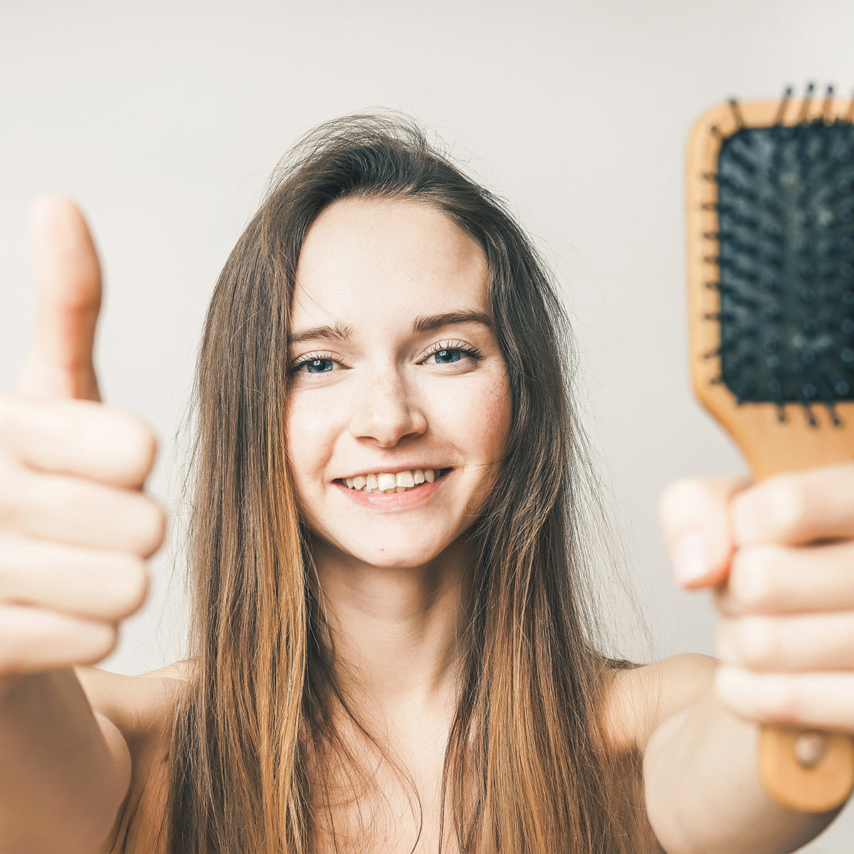 The woman is happy that she is losing less hair when she brushes her hair.