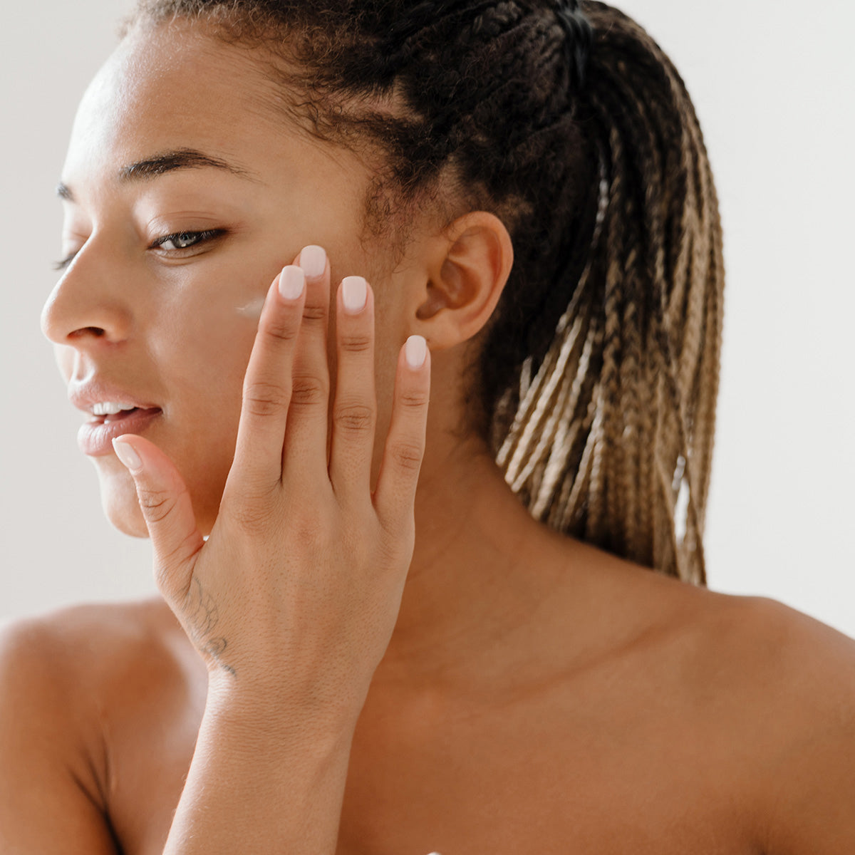 A woman using Hyaluronic Acid Lotion to help with hydration and moisturizing