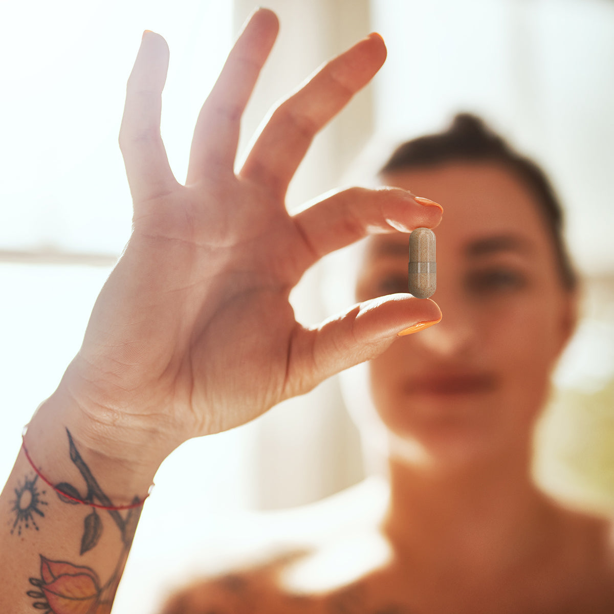 Woman holding an UnTangled Hair Supplement pill