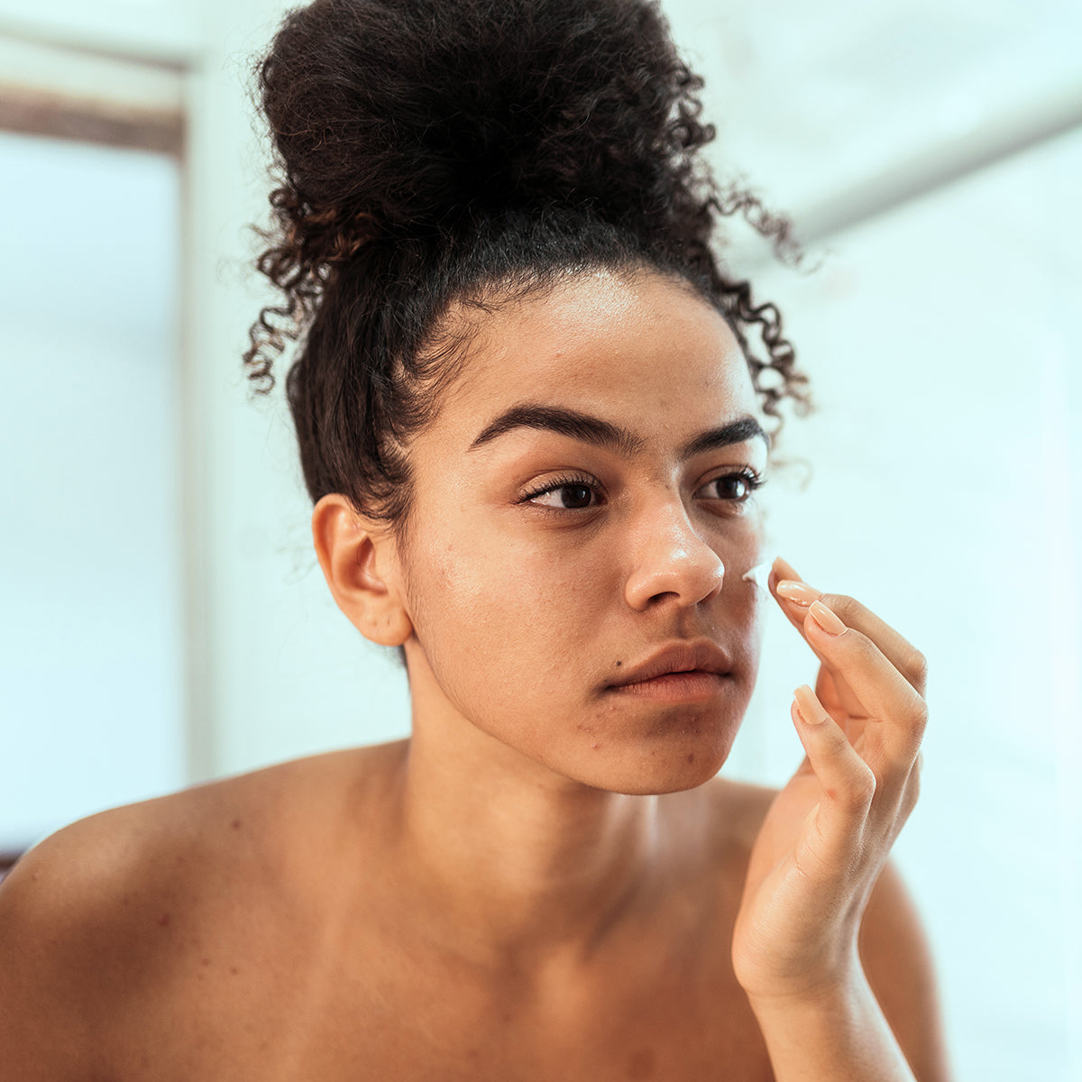 A woman is putting on azelaic acid 14% cream to help with redness and irritation