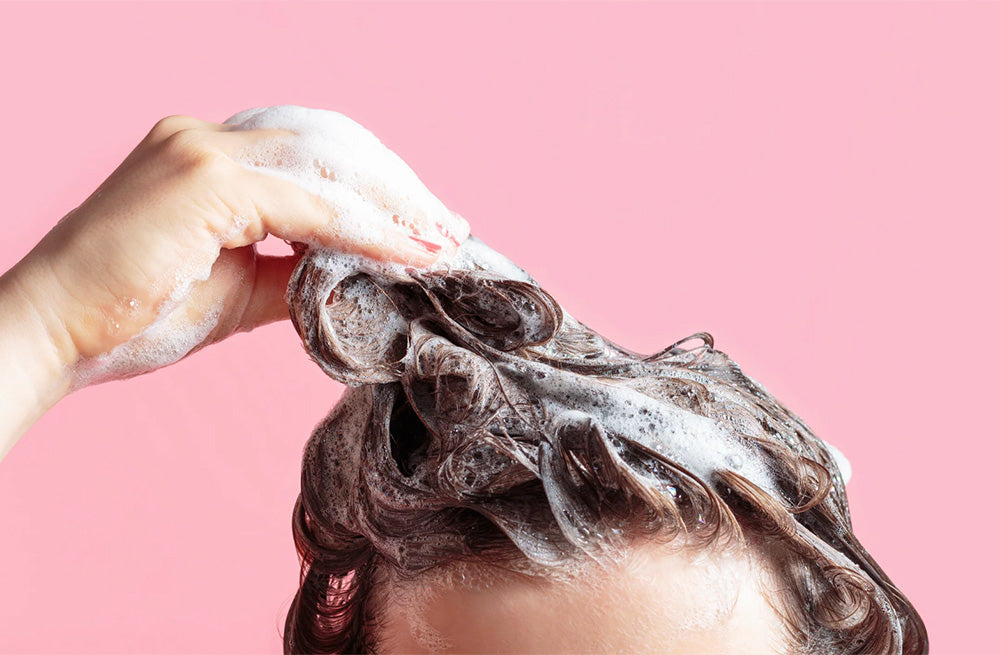 Top of head with shampoo against pink