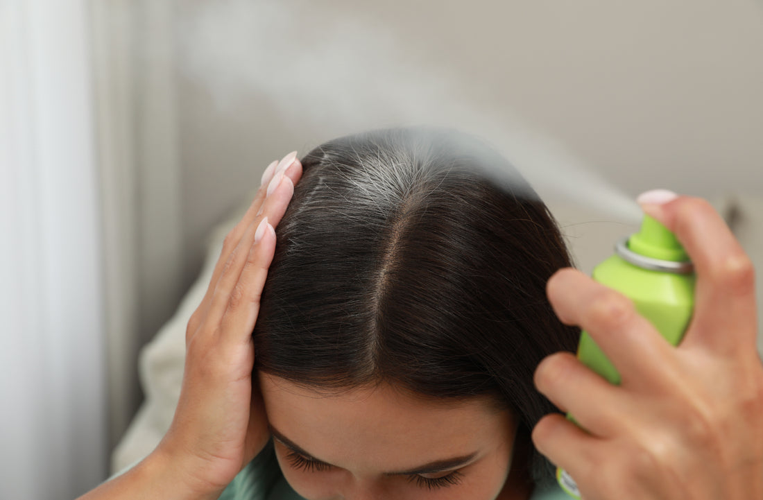 woman spraying dry shampoo on her brown hair roots