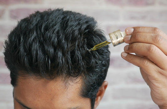 man putting hair serum in his hair with a dropper