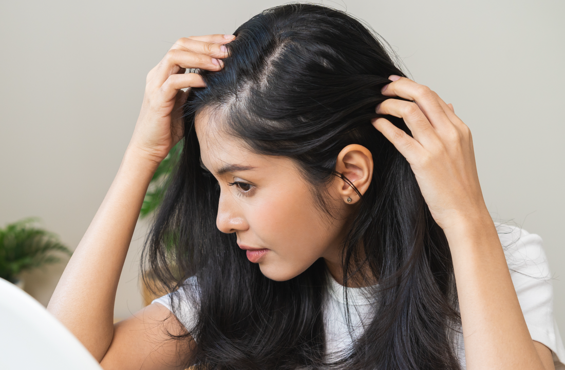 woman looking at her hair roots in the mirror