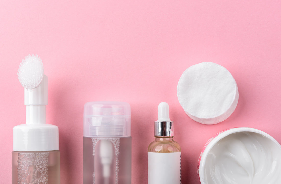 layout of different skincare products against a pink background